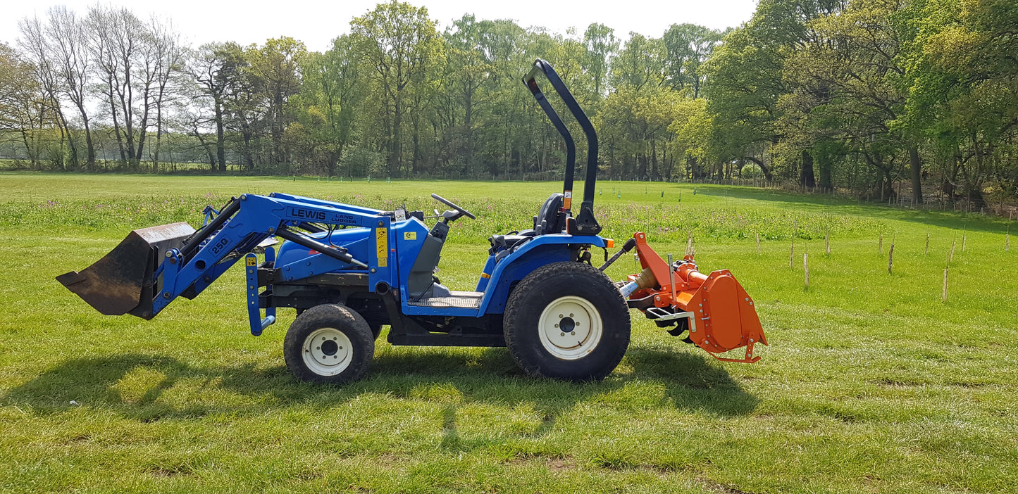 Small blue tractor with a FarmMaster tractor rotavator in a grassy field