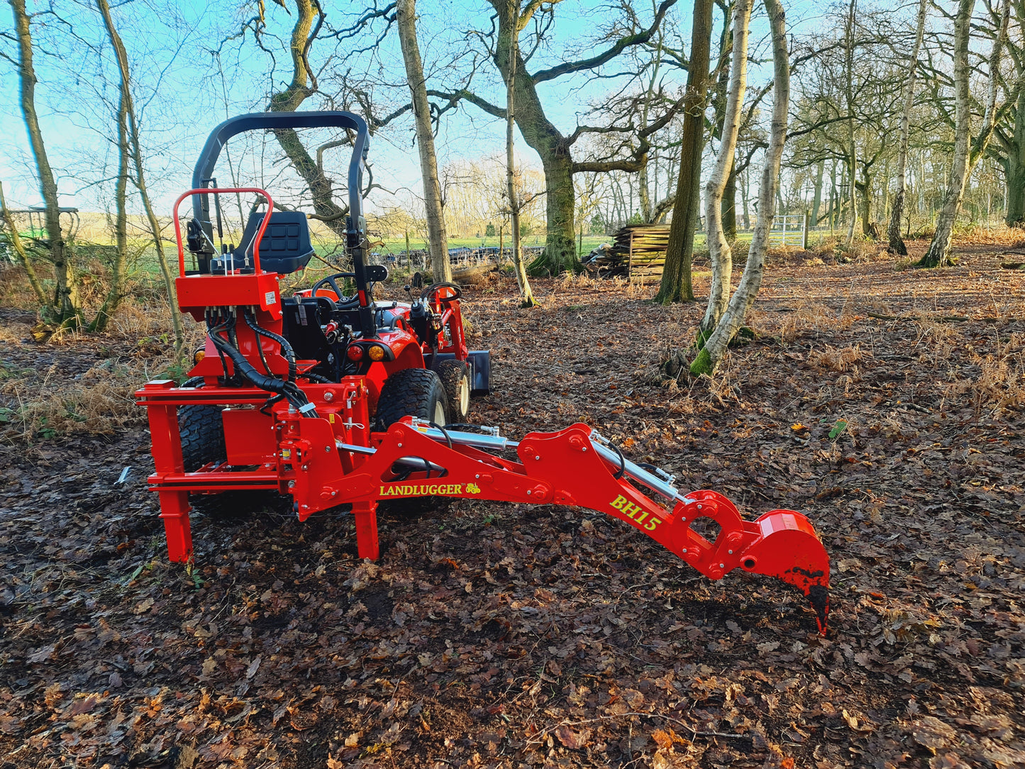 FarmMaster LandLugger tractor backhoe on a forest floor with trees in the background