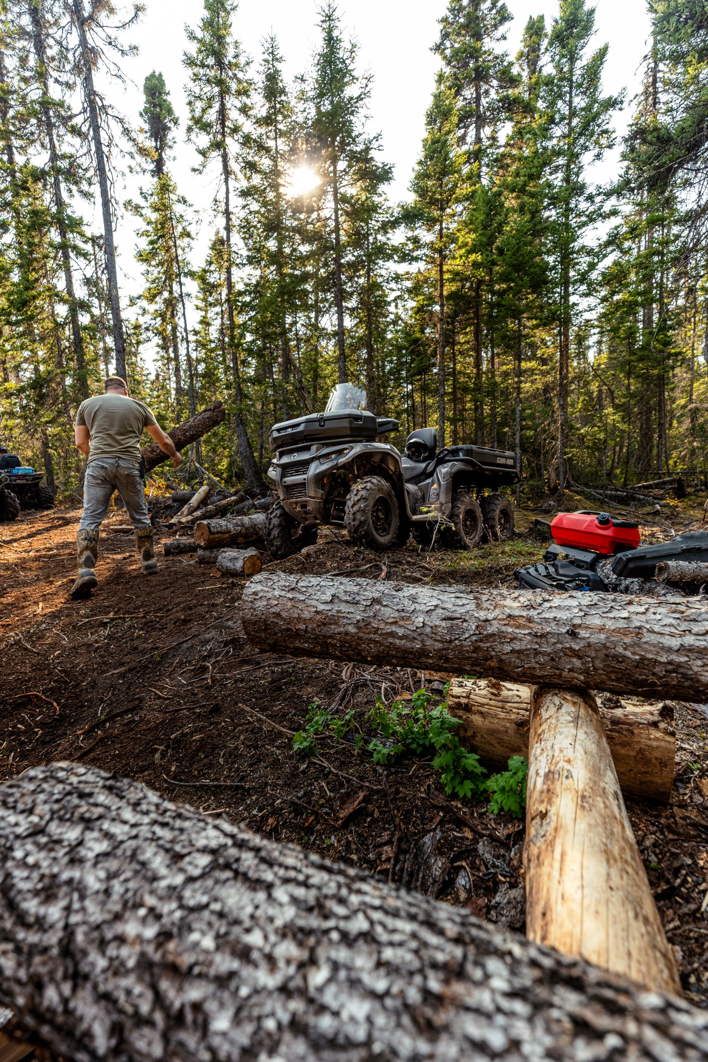 Person working with a Can-Am 6x6 ATV a forested area