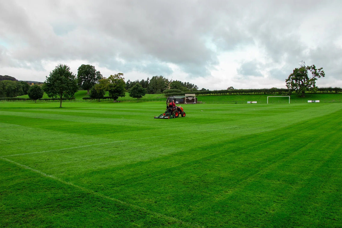 Wessex finishing mower with trees and a cloudy sky in the background.