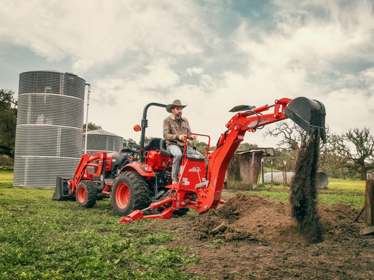 Person operating a Kioti tractor with backhoe loader.