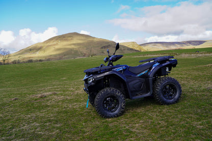 Black CFMOTO ATV parked on a grassy field with hills in the background