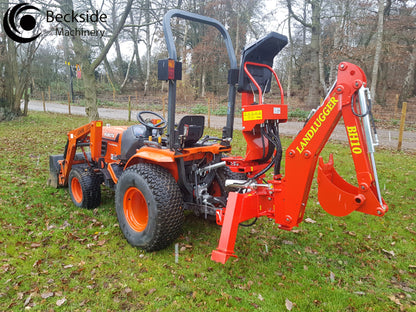 Orange tractor with a FarmMaster LandLugger tractor backhoe attachment on a grassy area.