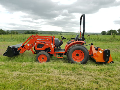 Kioti tractor with flail attachment in a grassy field under a cloudy sky