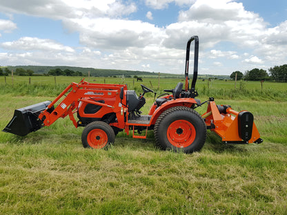 Kioti tractor with flail attachment in a grassy field under a blue sky with clouds.