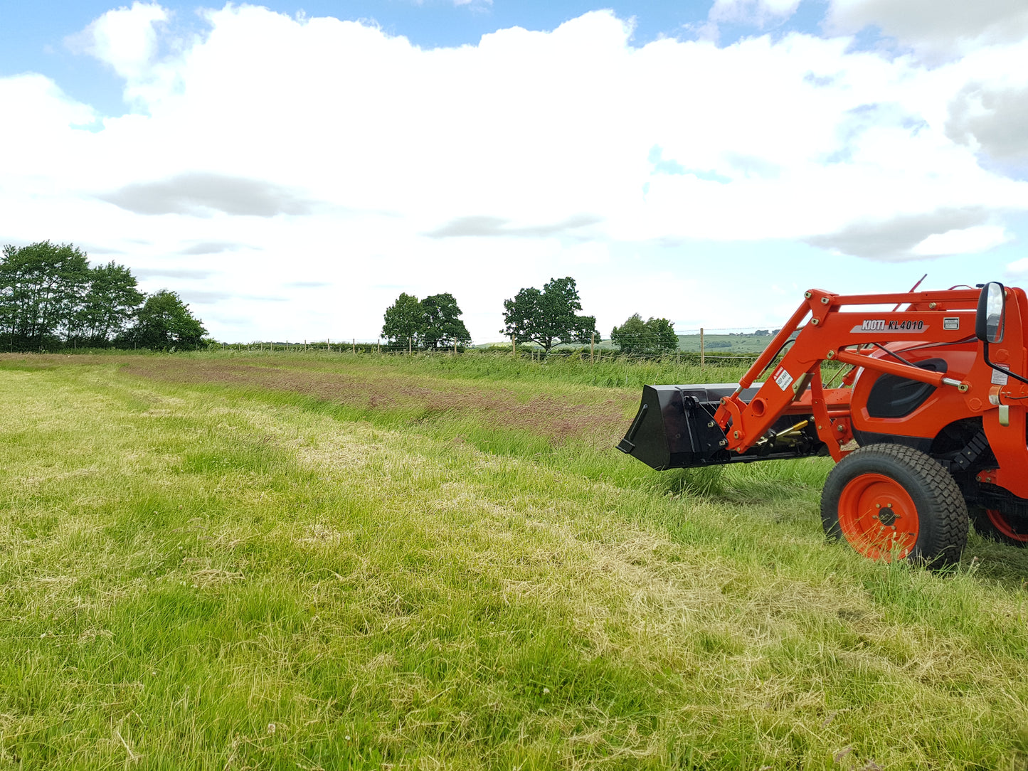 Kioti tractor in a wildflower field with a clear sky