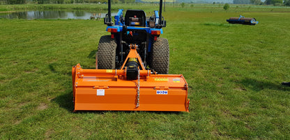 Tractor with an attached FarmMaster tractor rotavator attachment on a grassy field.