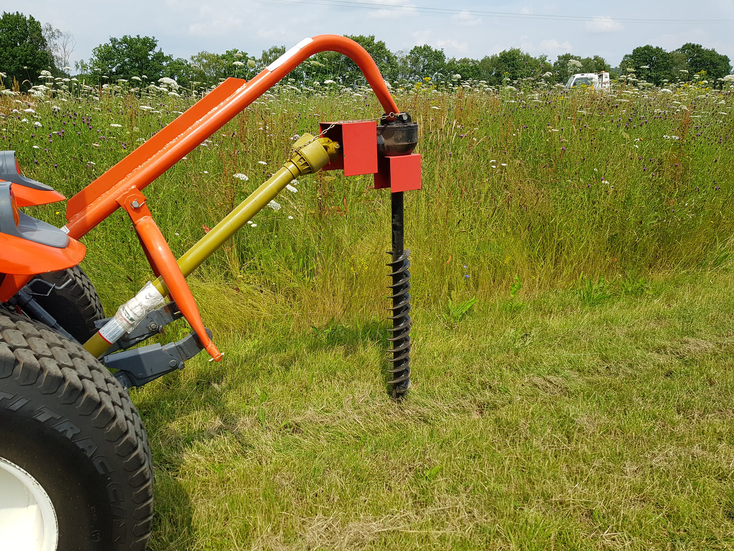 FarmMaster tractor post hole borer attached to a tractor in a field