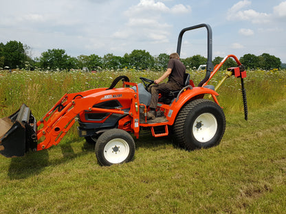 Orange tractor with a FarmMaster tractor post hole borer in a grassy field