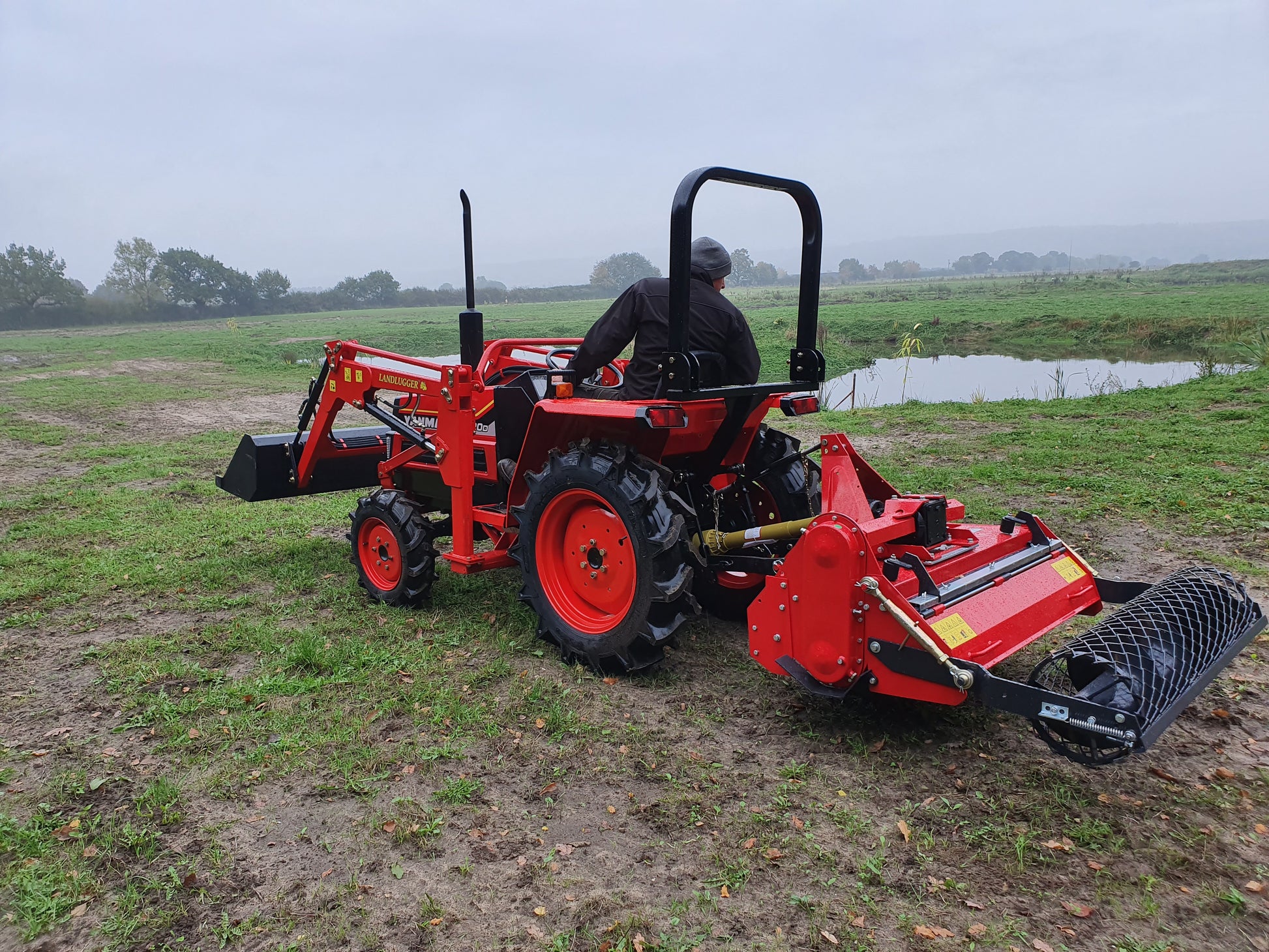 Red tractor with FarmMaster tractor stone burier  in a field on a cloudy day
