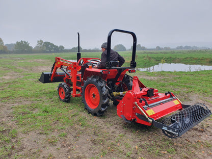 Kubota tractor with FarmMaster tractor stone burier in a field on a cloudy day