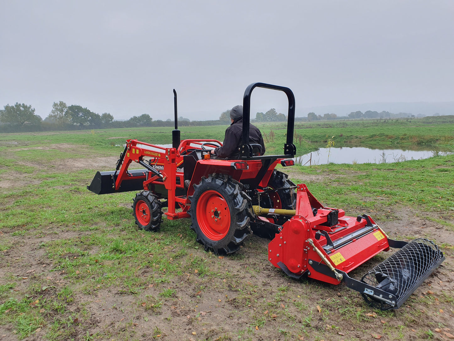 Red tractor with FarmMaster tractor stone burier  in a field on a cloudy day