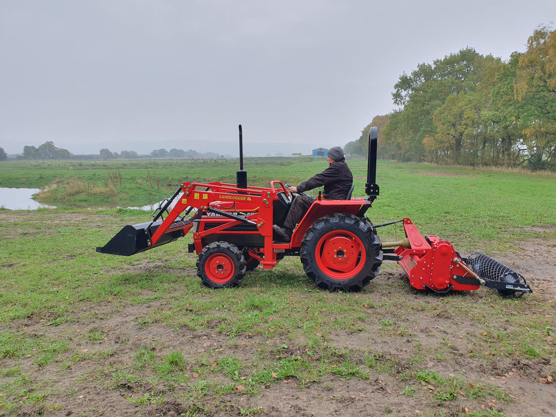 Red tractor with FarmMaster tractor stone burier on a grassy field