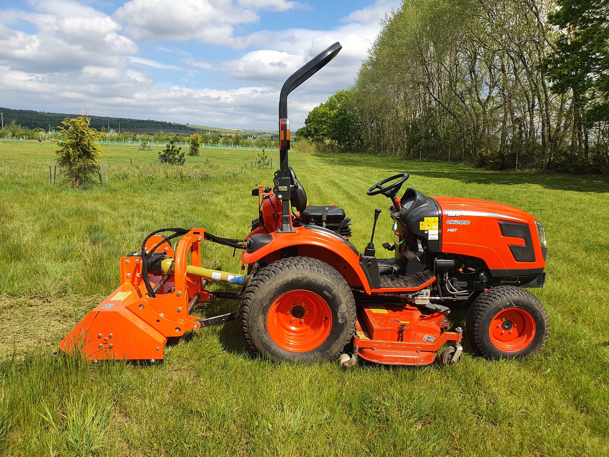 Orange tractor with attachments in a grassy field
