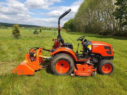 Orange tractor with attachments in a grassy field