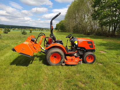 FarmMaster offset flail mower  on a grassy field with trees and blue sky.