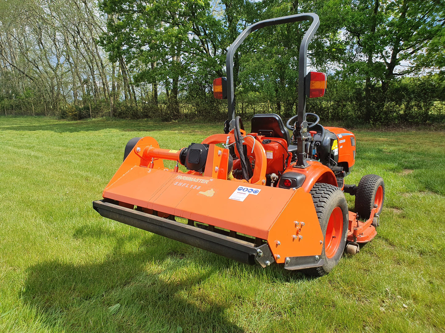FarmMaster offset flail mower  on a grassy field with trees in the background