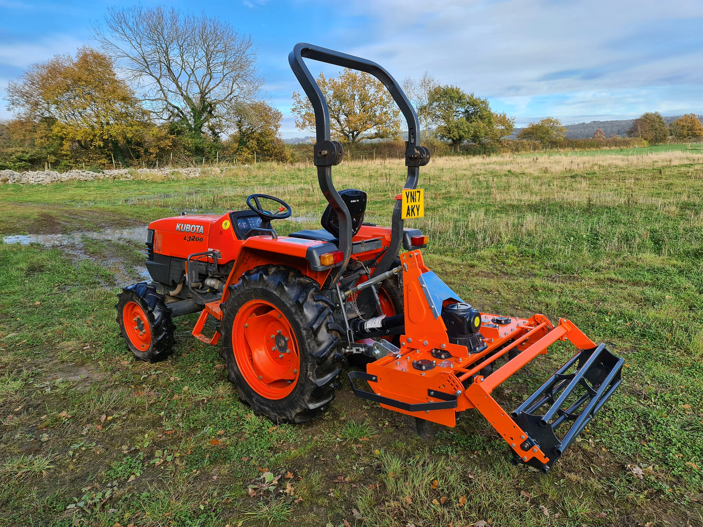 Orange tractor with a FarmMaster power harrow in a field