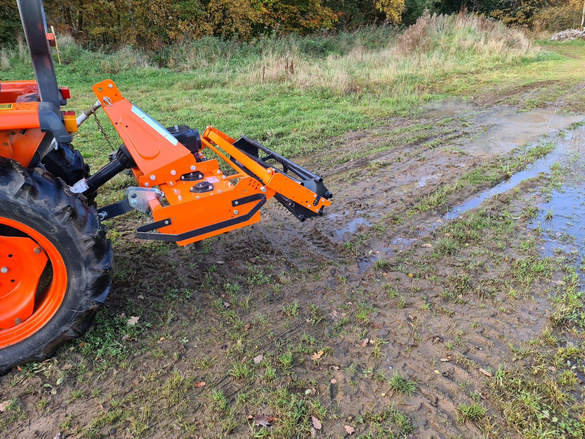 Tractor with a FarmMaster power harrow attachment on a muddy field