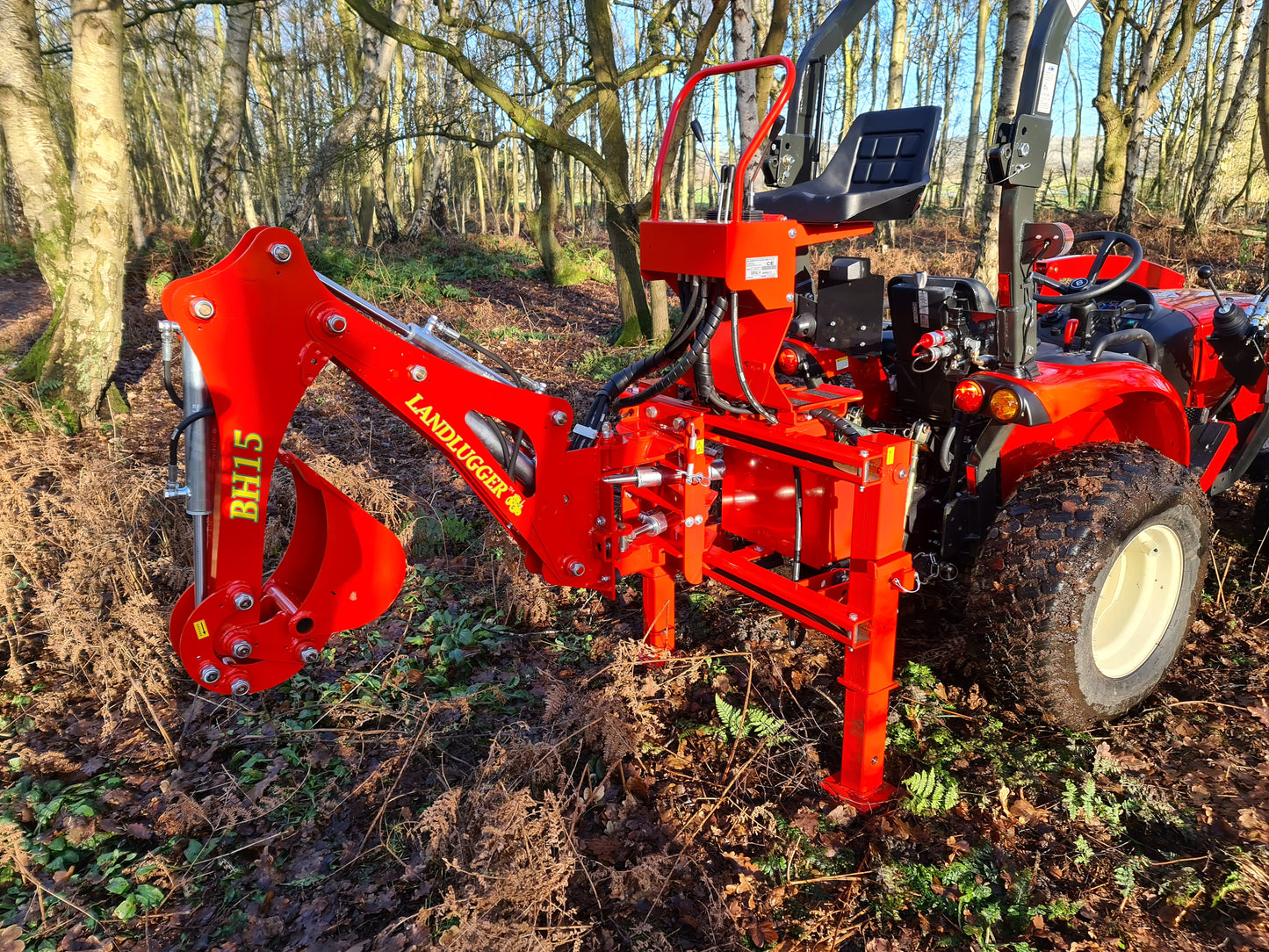 FarmMaster LandLugger tractor backhoe in a forest setting