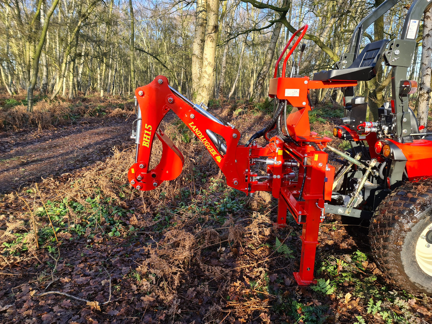 FarmMaster LandLugger tractor backhoe attached to a tractor in a forest setting