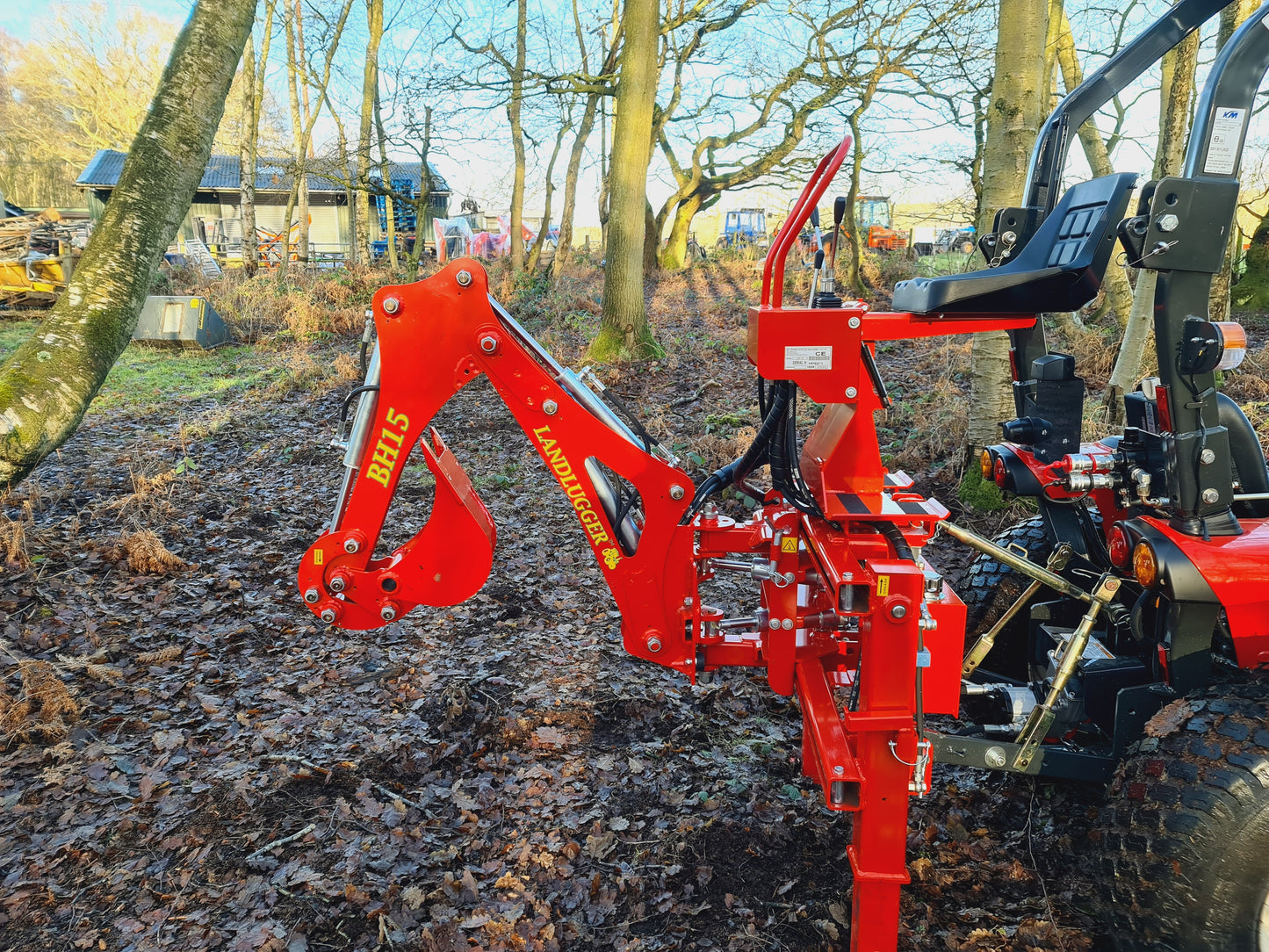 FarmMaster LandLugger tractor backhoe on a tractor in a wooded area