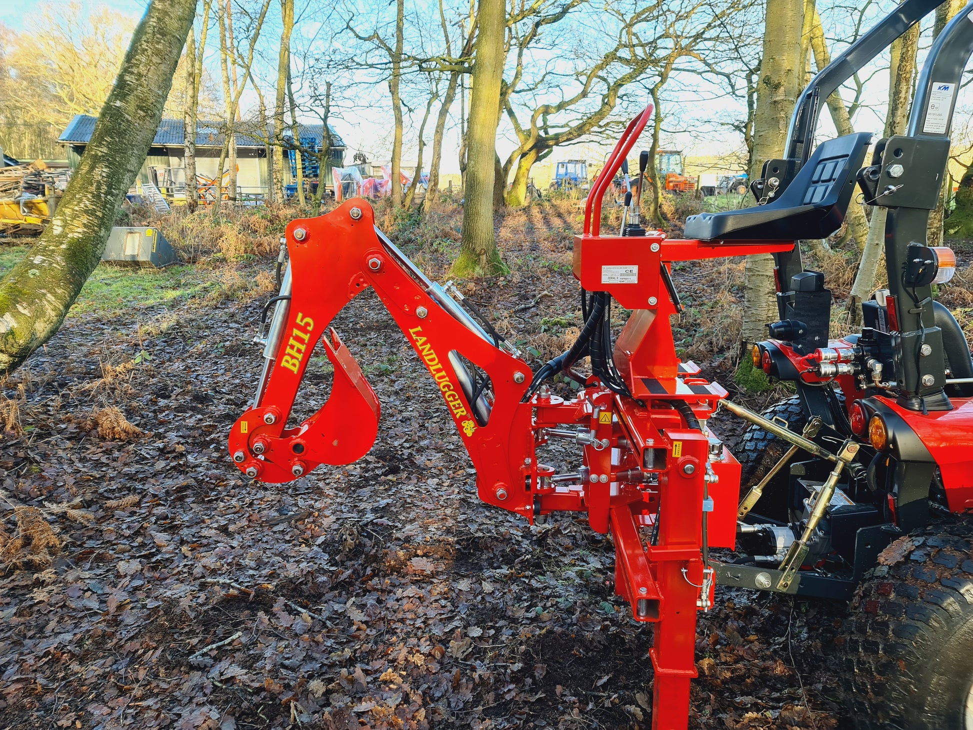 FarmMaster LandLugger tractor backhoe on a tractor in a wooded area
