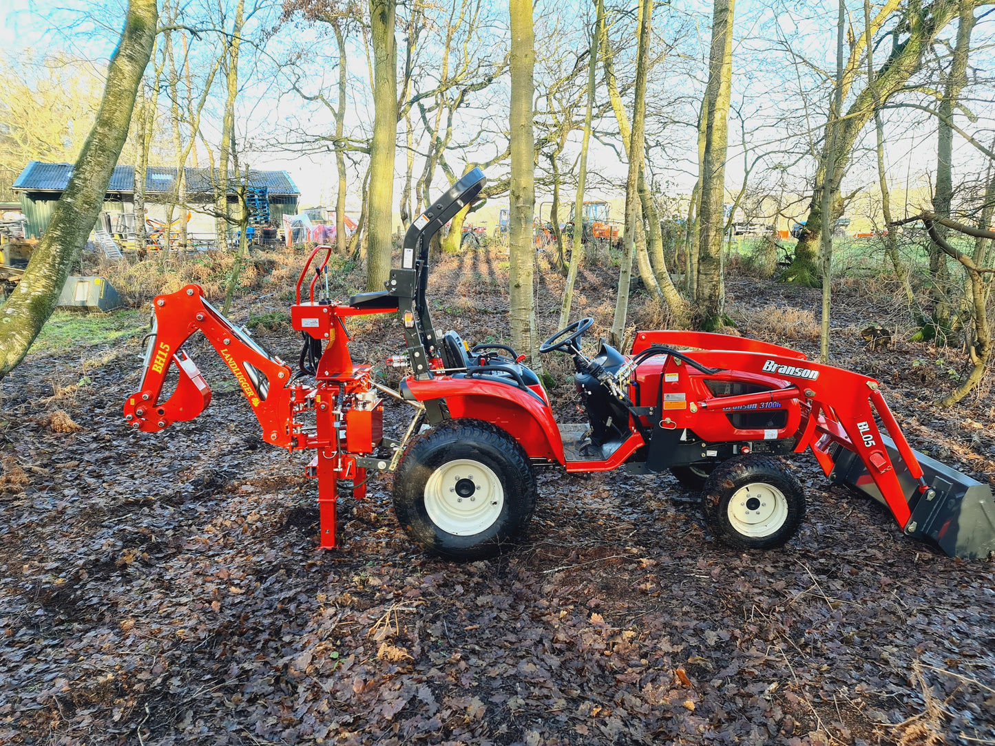 FarmMaster LandLugger tractor backhoe in a wooded area