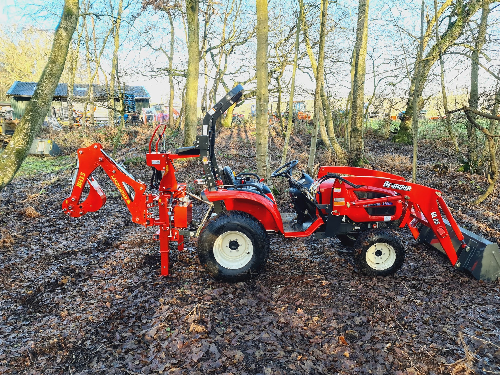 FarmMaster LandLugger tractor backhoe in a wooded area