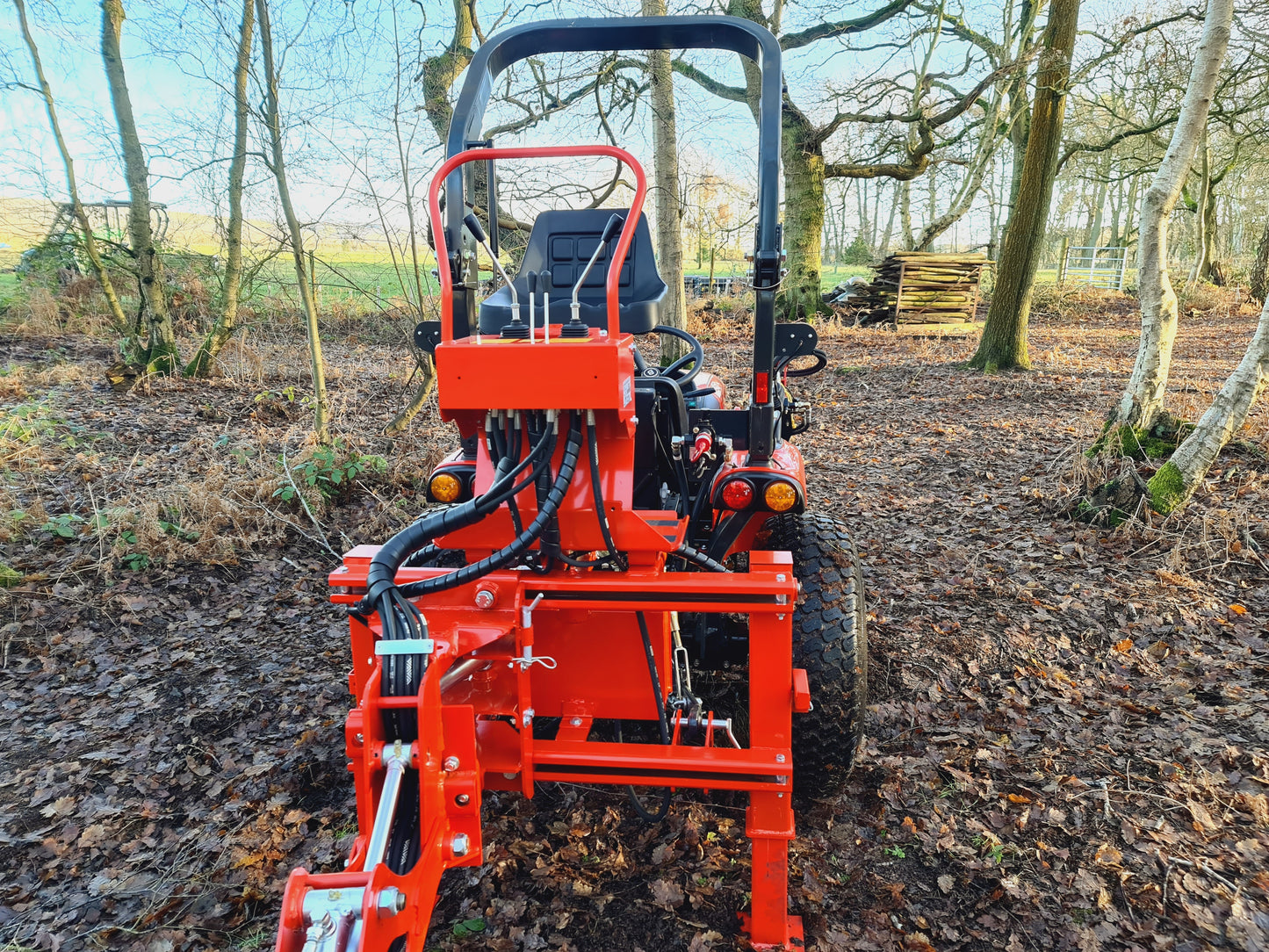 FarmMaster LandLugger tractor backhoe in a field with trees in the background
