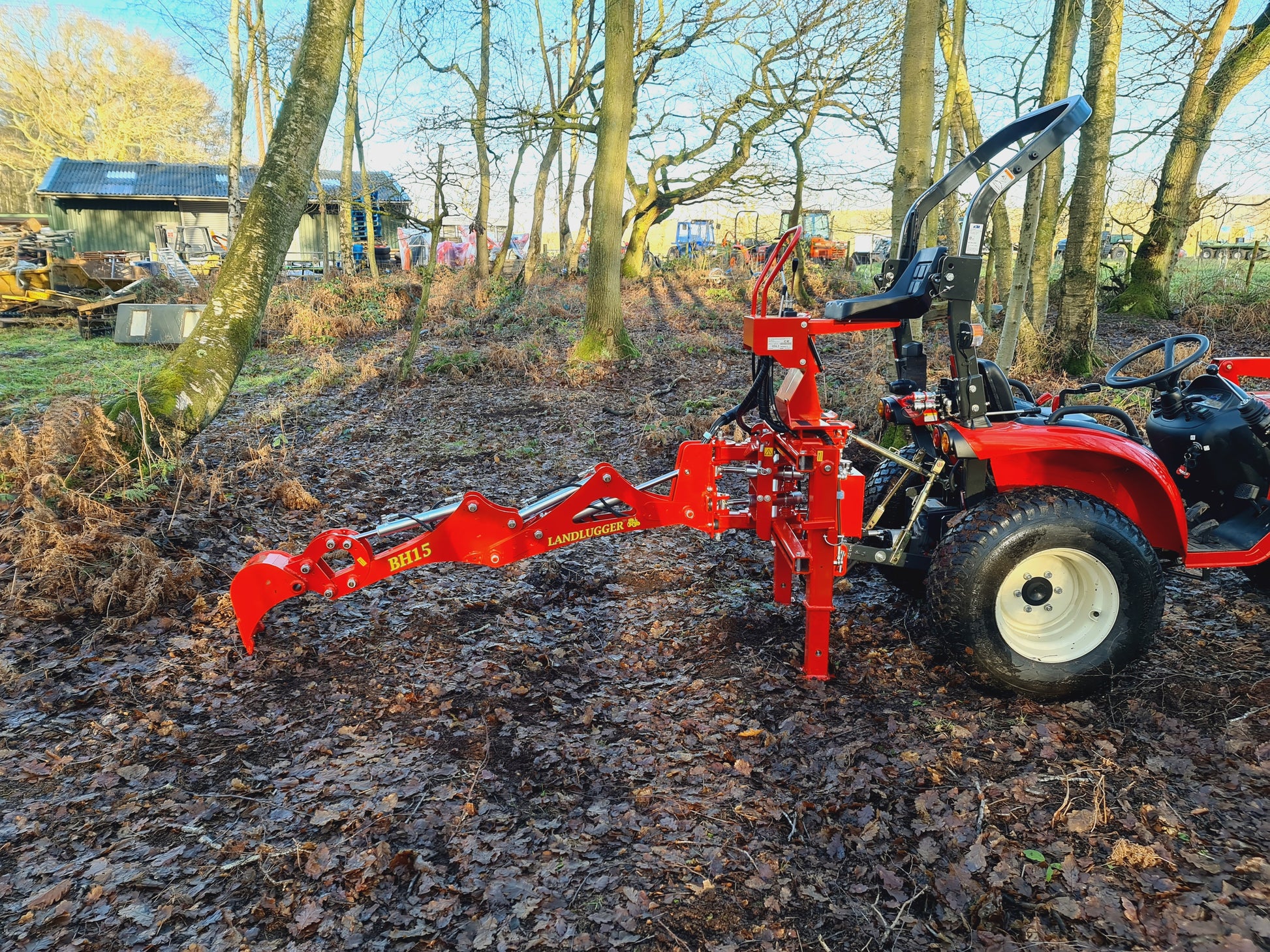FarmMaster LandLugger tractor backhoe attachment in a wooded area