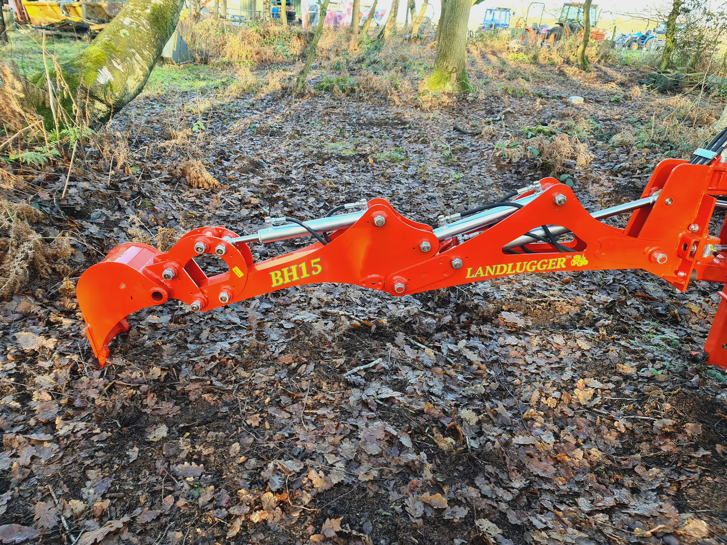 FarmMaster LandLugger tractor backhoe on a forest floor.
