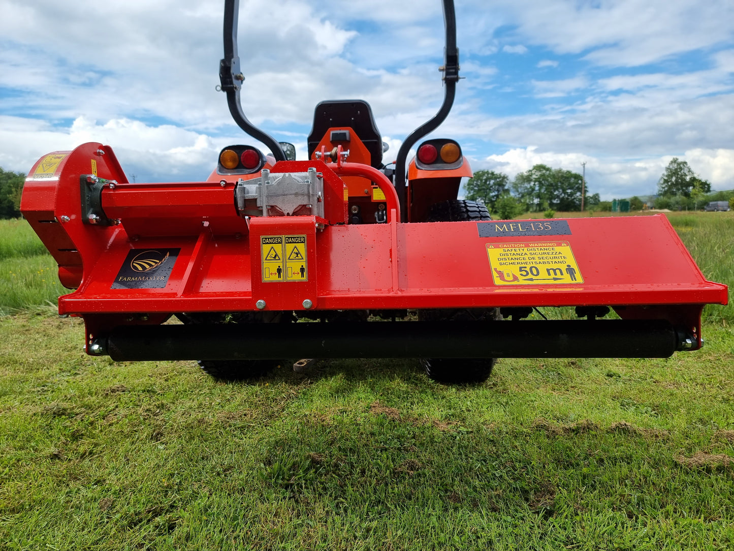 FarmMaster Pro offset flail mower  on a grassy field with a blue sky.
