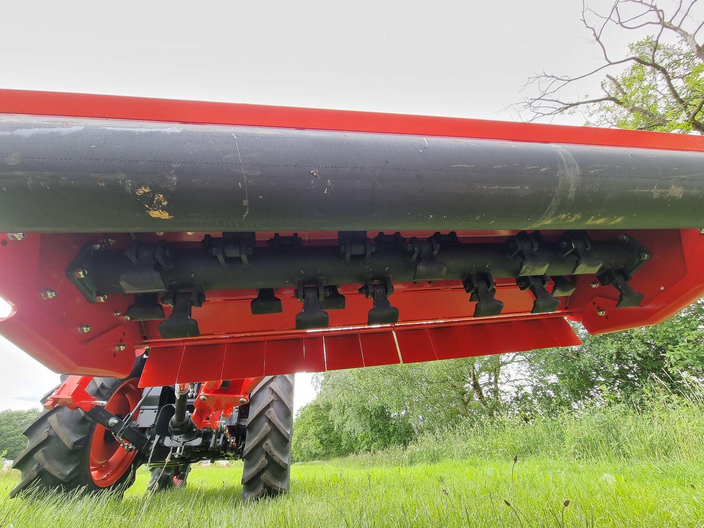 FarmMaster Verge Flail Mower in a field with green grass and trees in the background