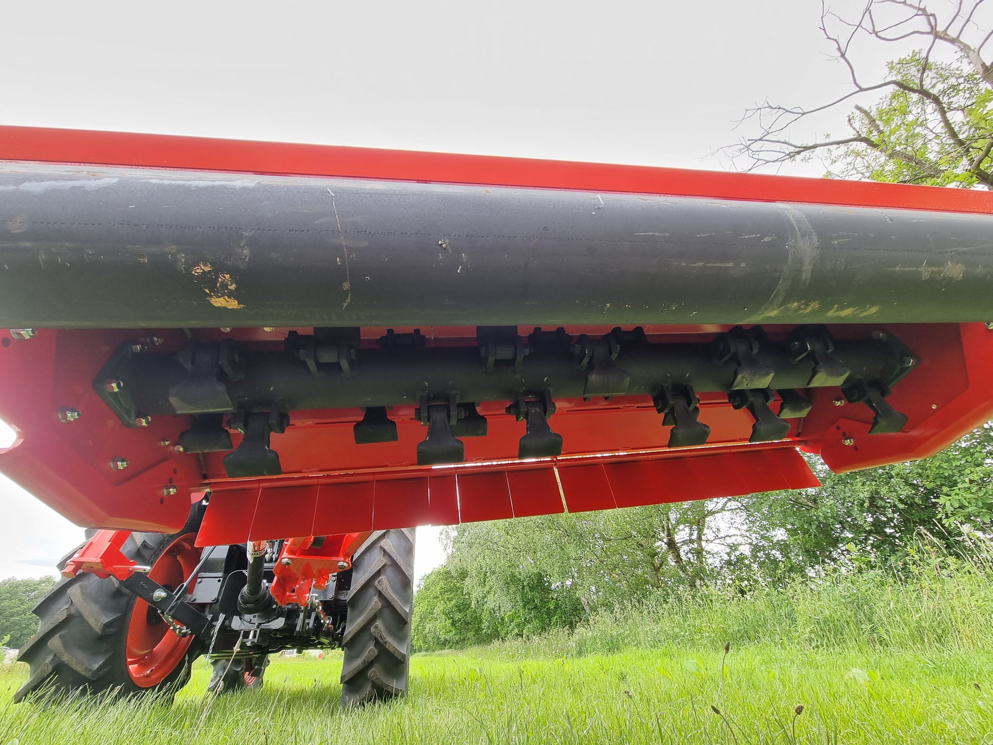 FarmMaster Verge Flail Mower in a field with green grass and trees in the background