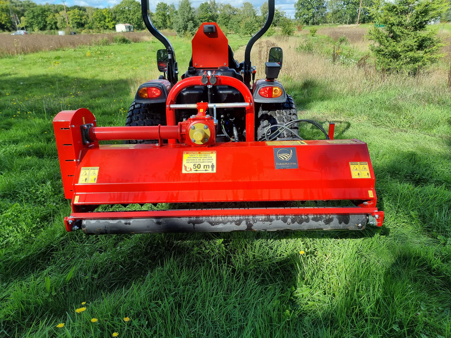 Red agricultural tractor with a large FarmMaster Pro Side-Shift flail mower 