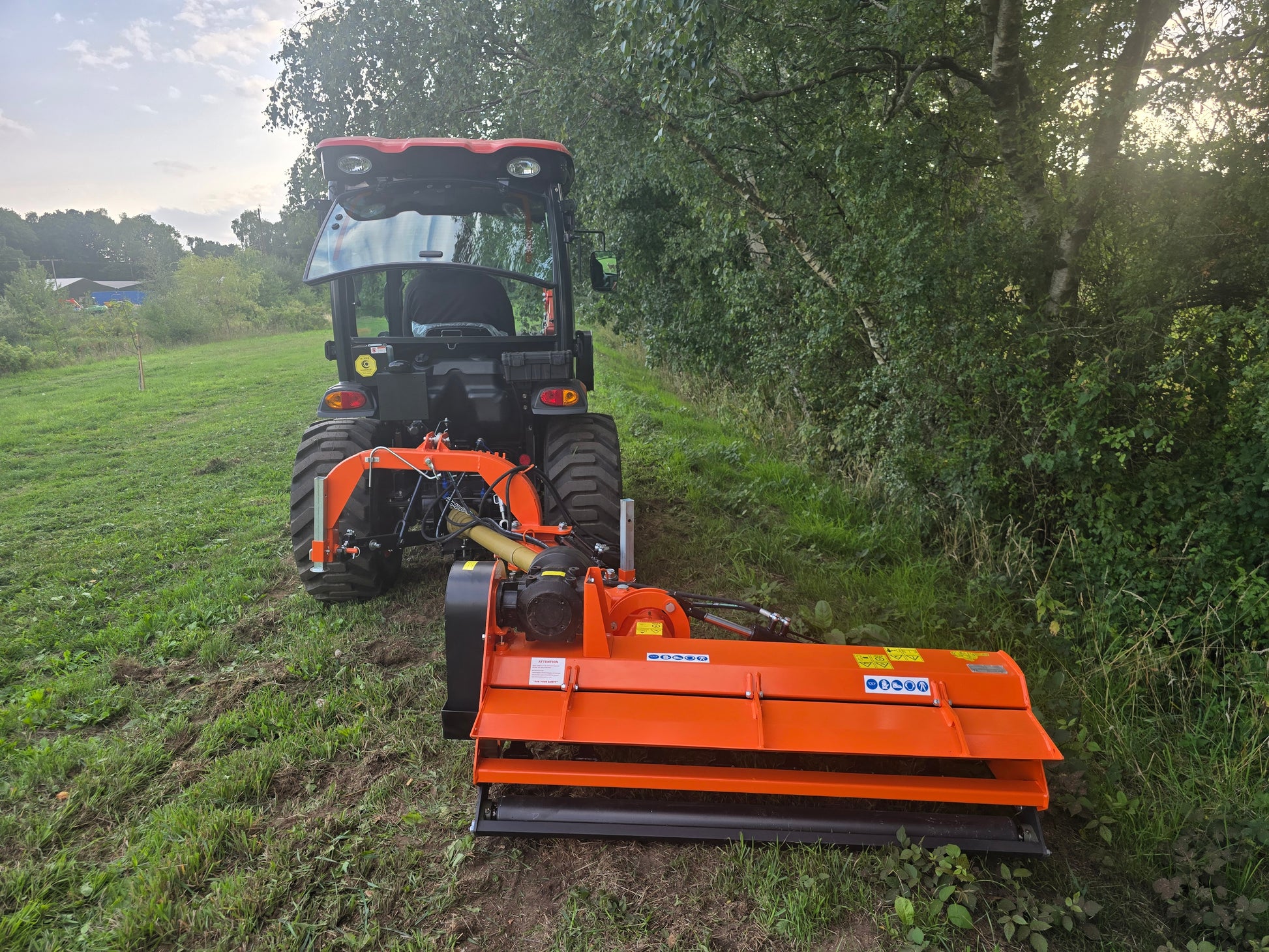 FarmMaster Verge Flail Mower attachment in a grassy field with trees in the background