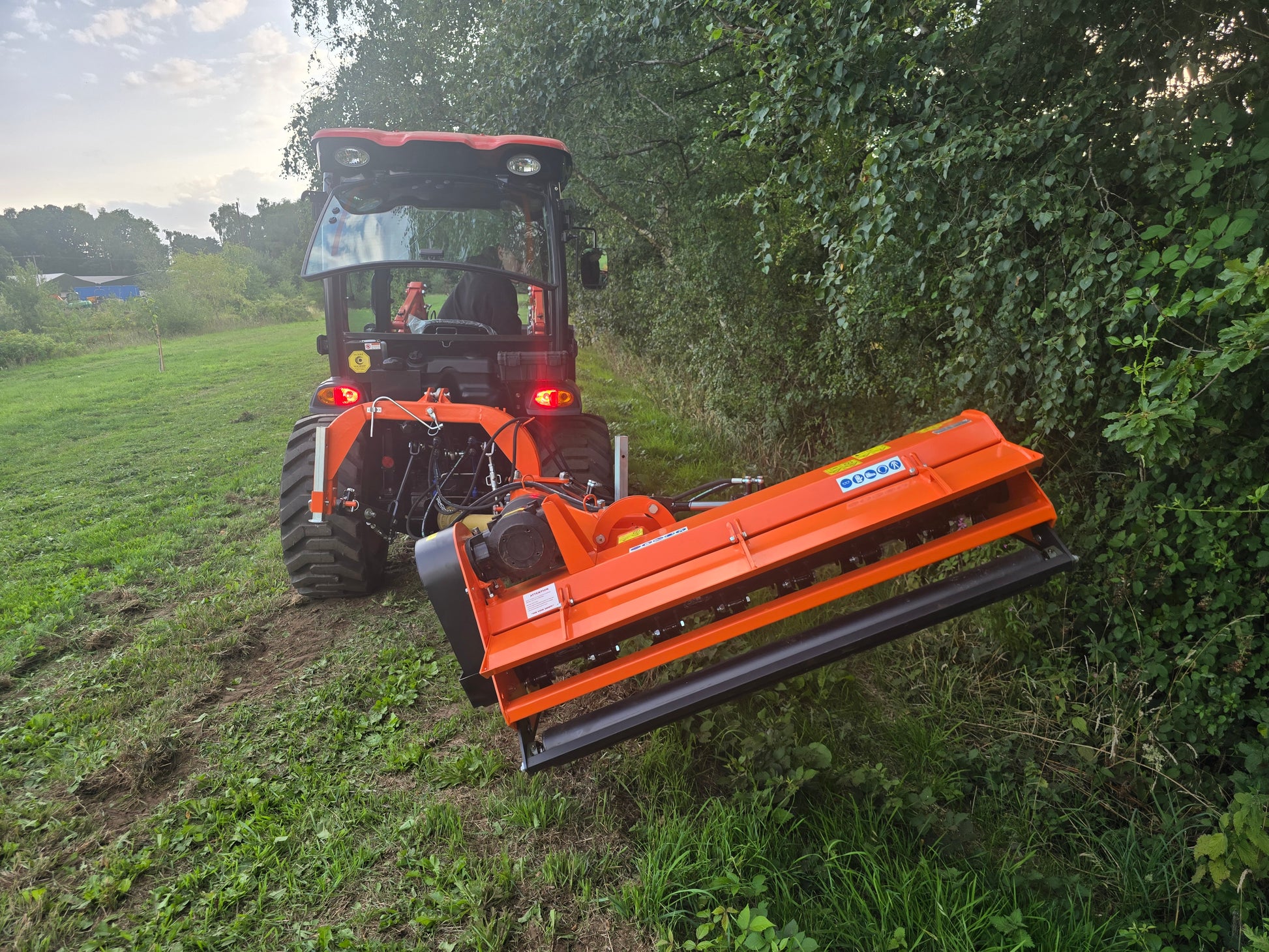 Tractor with a large FarmMaster Verge Flail Mower attachment cutting through grass and bushes