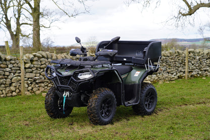 CFMOTO ATV parked on grass with stone wall and trees in the background