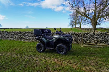Green CFMOTO 520 ATV parked on grass with stone wall and tree in the background