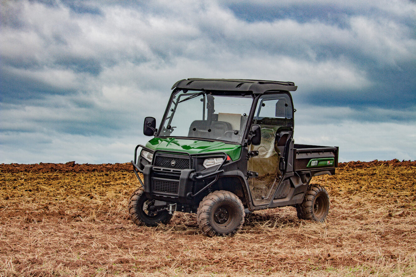 Kioti K9 utility vehicle in a field with a cloudy sky.