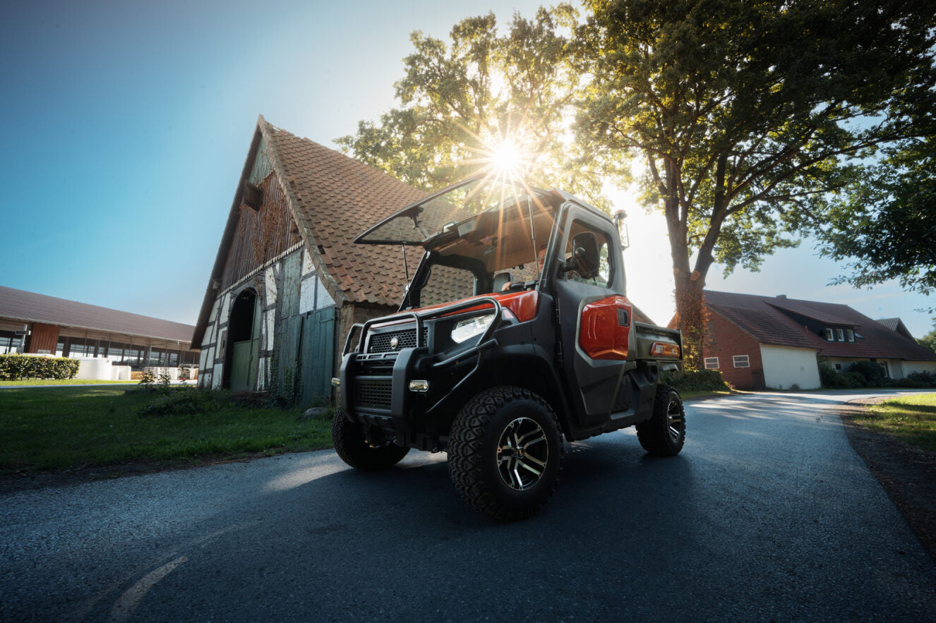 Kioti K9 UTV utility vehicle on a road with a barn and trees in the background