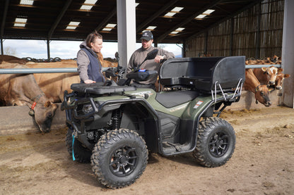 Two people with a CFMOTO 520 ATV in a barn with cows in the background