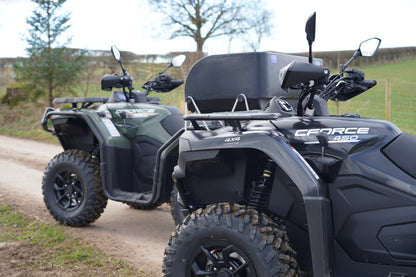 CFMOTO 450 and 520 ATVs on a dirt road with a grassy field in the background.