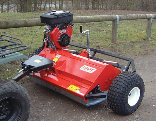 Logic ATV flail mower, surrounded by grass and trees.