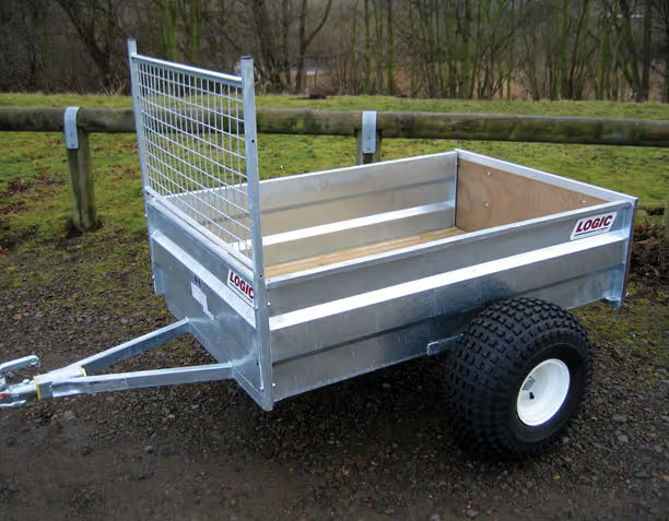 Logic ATV Trailer with a grid front on a dirt path, surrounded by grass and trees.