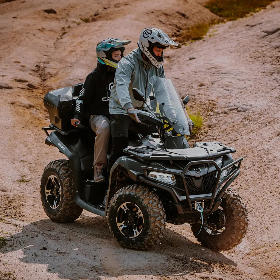 Two people on a CFMOTO ATV in a desert-like terrain