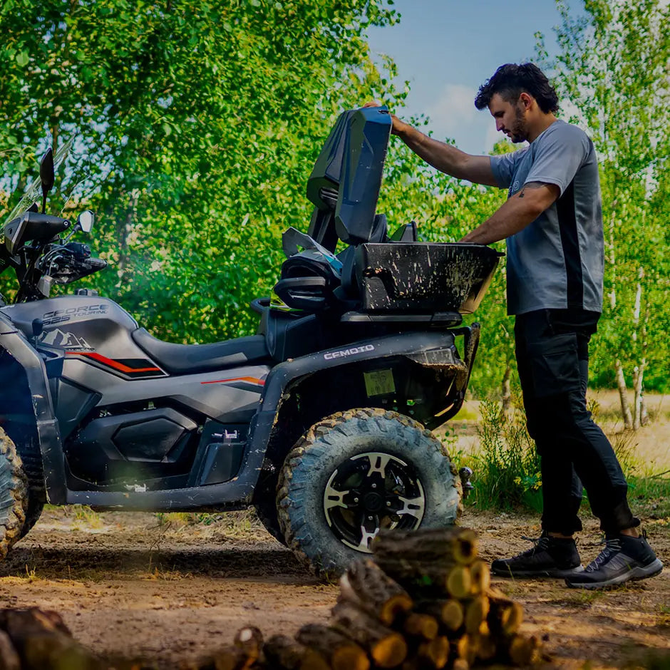 Man loading wood onto a CFMOTO ATV in a forest setting