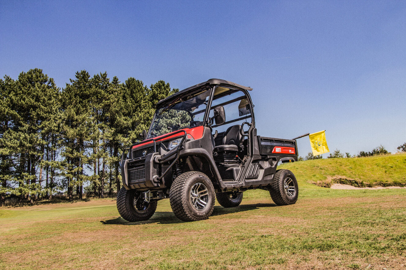 Kioti K9 on a golf course with trees in the background