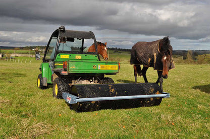Logic land roller in a field with two horses.